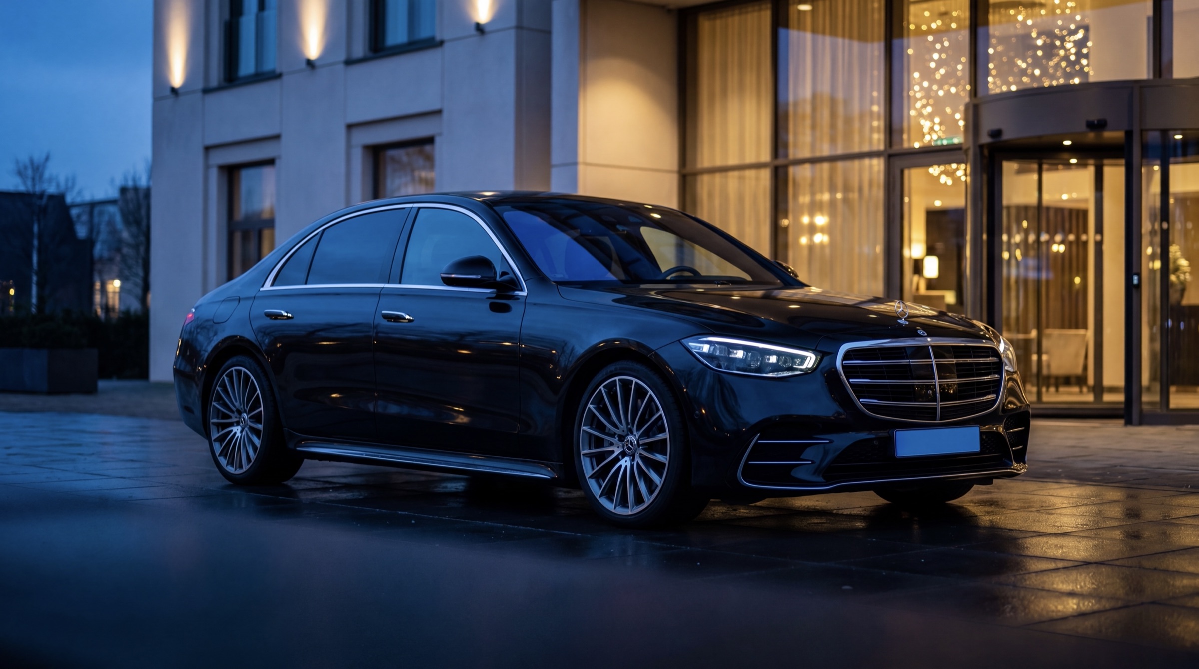 Mercedes S-Klasse wacht bij een luxe hotelentree in de schemering - chauffeur per uur